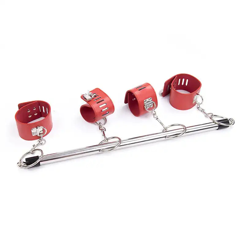 Vue d'ensemble de la barre d'écartement en acier équipée de quatre menottes rouges rembourrées, parfaite pour la sissification et le crossdressing.