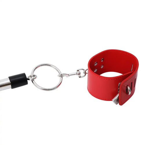 Gros plan sur la fixation d'une menotte rouge rembourrée sur la barre d'écartement en acier, accessoire bdsm et soumission pour la sissification sur Le Sissyshop.