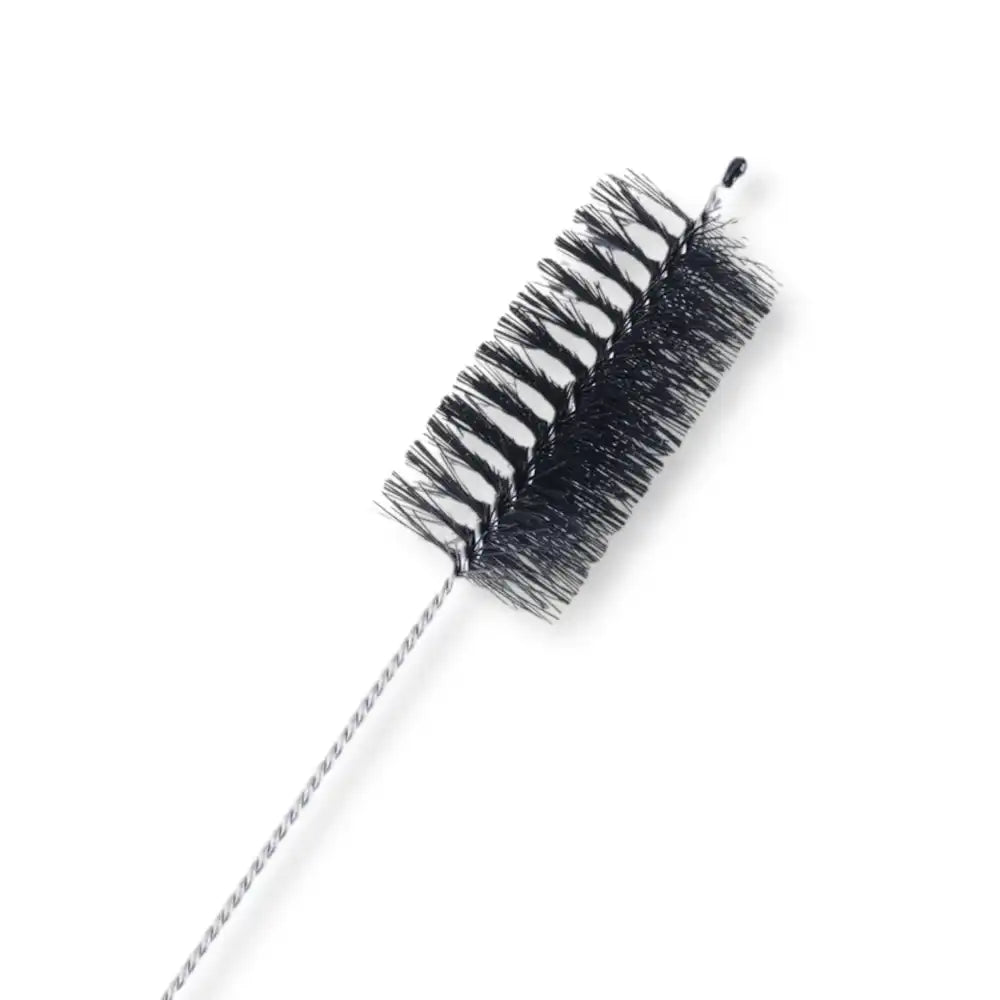 Gros plan sur une brosse de nettoyage fine en acier et poils noirs, accessoire d'entretien pour cage de chasteté homme et ceinture chasteté.