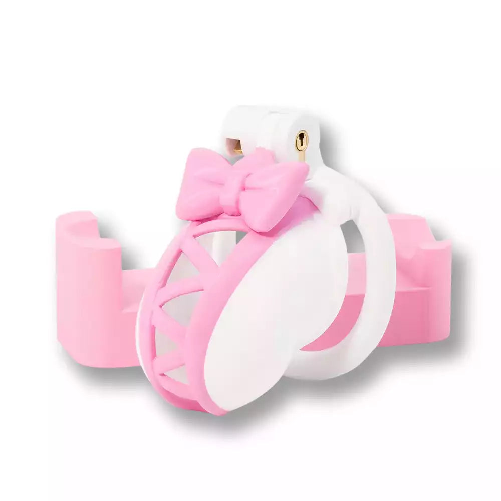 Présentation sur socle de la cage chastete homme bicolore ornée d'un nœud papillon rose, l'accessoire idéal pour affirmer sa féminisation avec élégance sur la boutique sissyshop.