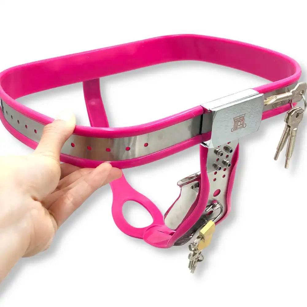 Main tenant une ceinture de chasteté en métal avec revêtement rose fuchsia et cadenas, la culotte de chasteté idéale pour s'initier à la sissification sur sissyshop.