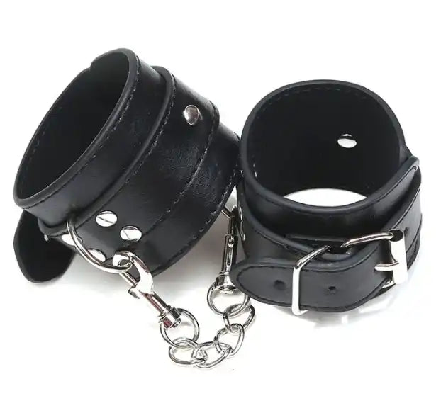 Menottes en cuir noir avec chaîne métallique et boucles ajustables, accessoire bdsm et selfbondage idéal pour la sissification sur Le Sissyshop.