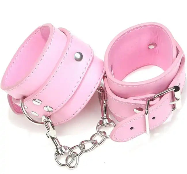 Menottes en cuir rose rembourrées avec chaîne et boucles de serrage, accessoire de féminisation et de soumission pour sissy.