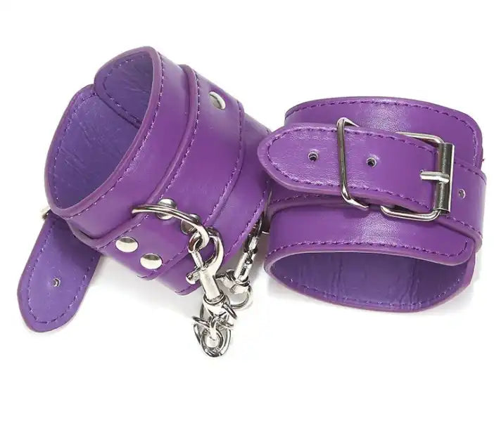 Menottes en cuir violet avec chaîne et rivets métalliques, équipement de bondage pour jeux de rôle et crossdressing sur Le Sissyshop.