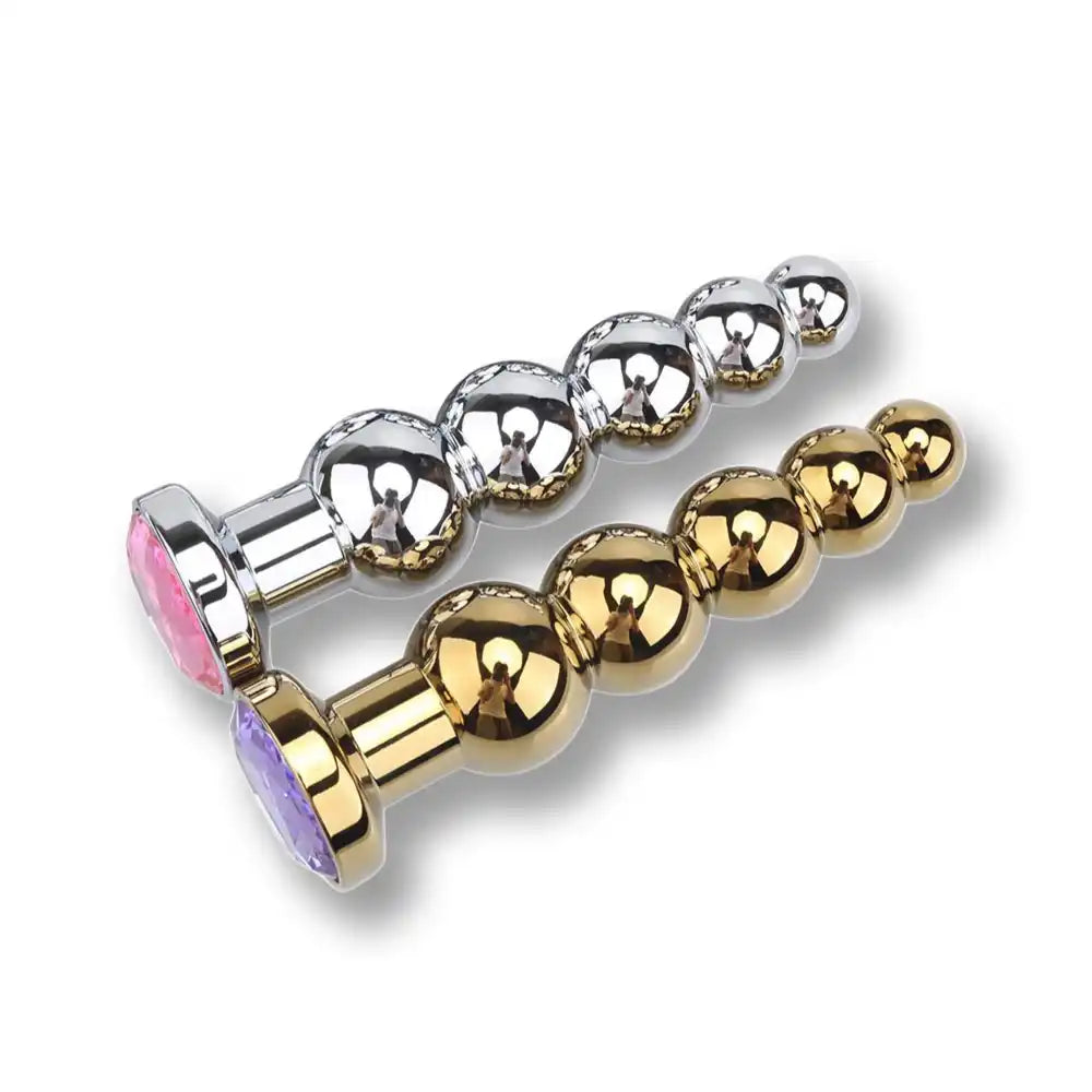 Vue comparative de plugs anaux en métal argent et or ornés de strass colorés, plug anal bijoux et accessoire de féminisation pour adultes.