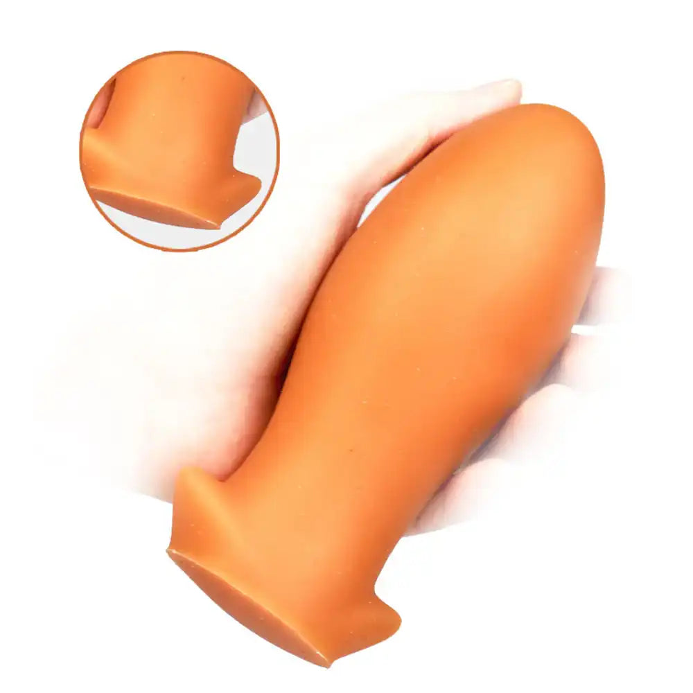 Gros plan sur la base évasée sécurisée du plug anal Dragon Egg en silicone orange.