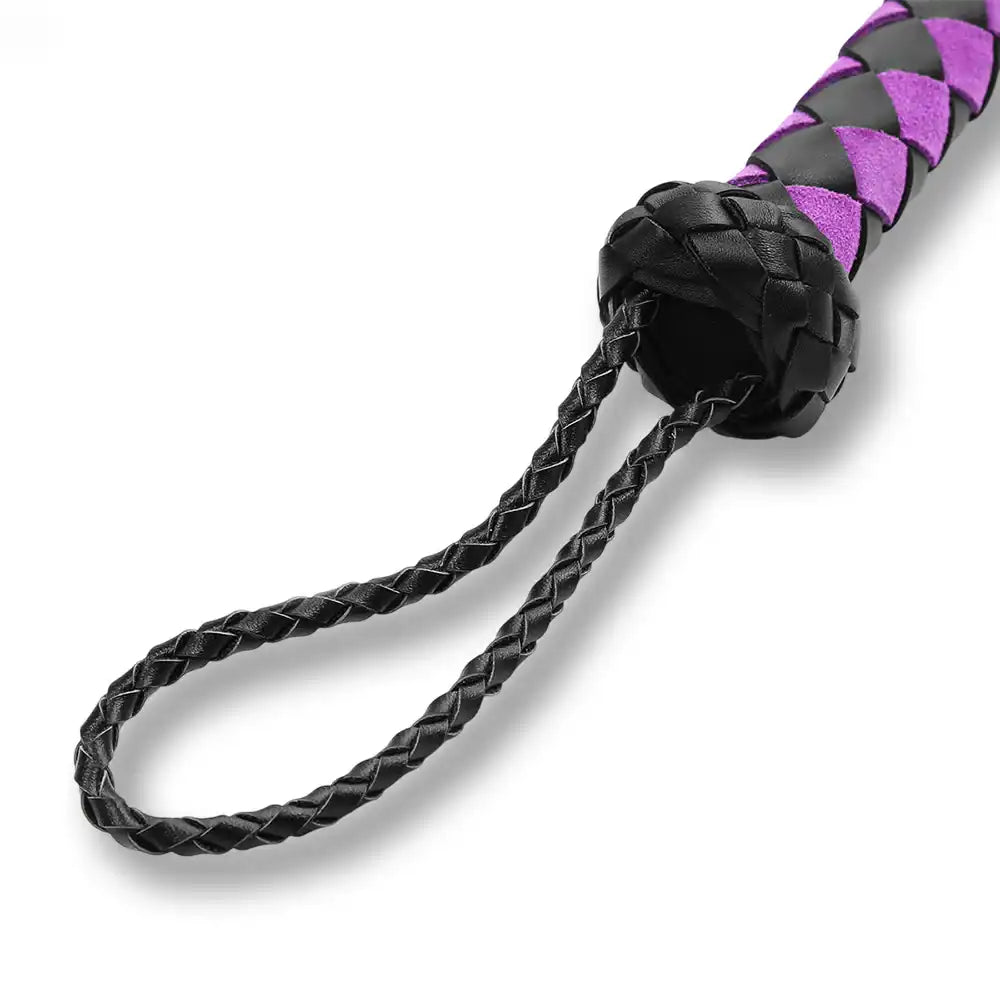 Gros plan sur la poignée tressée et la dragonne en cuir d'un flogger de soumission, finition haut de gamme pour jeux érotiques.