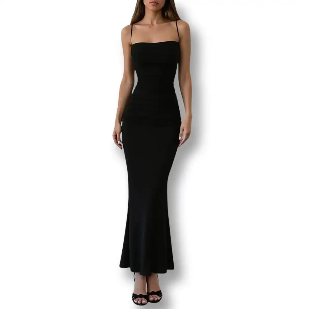 Silhouette en pied portant la robe longue noire moulante avec des talons, idéale pour les amateurs de relooking féminin.